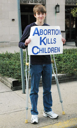 Bobby Vogel, a member of St. Joseph Parish in Jennings County, leans on crutches while he prays during the Central Indiana Life Chain on Oct. 4 along North Meridian Street in Indianapolis. (Photo by Mary Ann Wyand) 