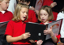 St. Jude School fourth-graders Samantha Curtis, left, and Alexandra Lawson of Indianapolis sing during the opening session of the “Spreading Hope in Neighborhoods Everywhere” conference on Oct. 1 at Lucas Oil Stadium in Indianapolis. In their workshop, archdiocesan youth and young adult ministry leaders Mary Schaffner and Kay Scoville urged parish leaders to connect the Eucharist to works of social ministry. (Photo by Mary Ann Wyand) 