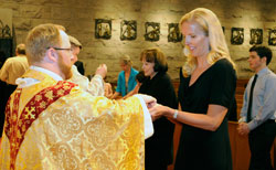 Carolyn Scott receives her first Communion from Father Joseph Newton, associate pastor of St. Luke the Evangelist Parish in Indianapolis, on April 3 during the Easter Vigil Mass at the parish church. Scott and her 8-year-old daughter, Mallory, were received into the full communion of the Church during the liturgy. (Submitted photo by Walt Kuhn)