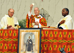 Divine Word Father Sam Cunningham, associate pastor of St. Patrick Parish in Fort Wayne, Ind., in the Diocese of Fort Wayne-South Bend, elevates the Eucharist during the St. Martin de Porres feast day Mass on Nov. 3 at St. Luke the Evangelist Church in Indianapolis. Father Steven Schwab, left, pastor of St. Thomas Aquinas Parish in Indianapolis, and Father Kenneth Taylor, right, pastor of Holy Angels Parish in Indianapolis and director of the archdiocesan Office of Multicultural Ministry, concelebrated the liturgy. (Photos by Mary Ann Garber)