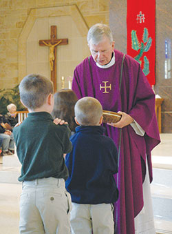 Msgr. Paul Koetter distributes Communion during a school Mass on April 16 at Holy Spirit Church in Indianapolis. (Photo by John Shaughnessy)