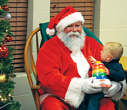 A small boy sits on the lap of Santa Claus during a Christmas party at Holy Family Shelter in Indianapolis, where the staff and volunteers work hard to make Christmas special for homeless families. (Submitted photo)