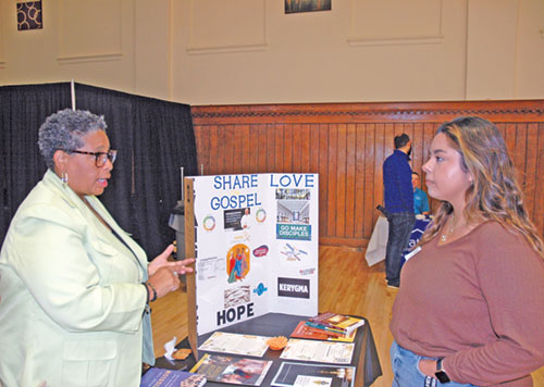 Anita Bardo, left, the archdiocese’s coordinator of evangelization and discipleship, explains a point to Alejandra Aguilar, associate youth minister at St. Simon the Apostle Parish in Indianapolis, during a ministry fair for new parish ministry leaders at the Archbishop Edward T. O’ Meara Catholic Center in Indianapolis on Sept. 17. (Photo by John Shaughnessy) 